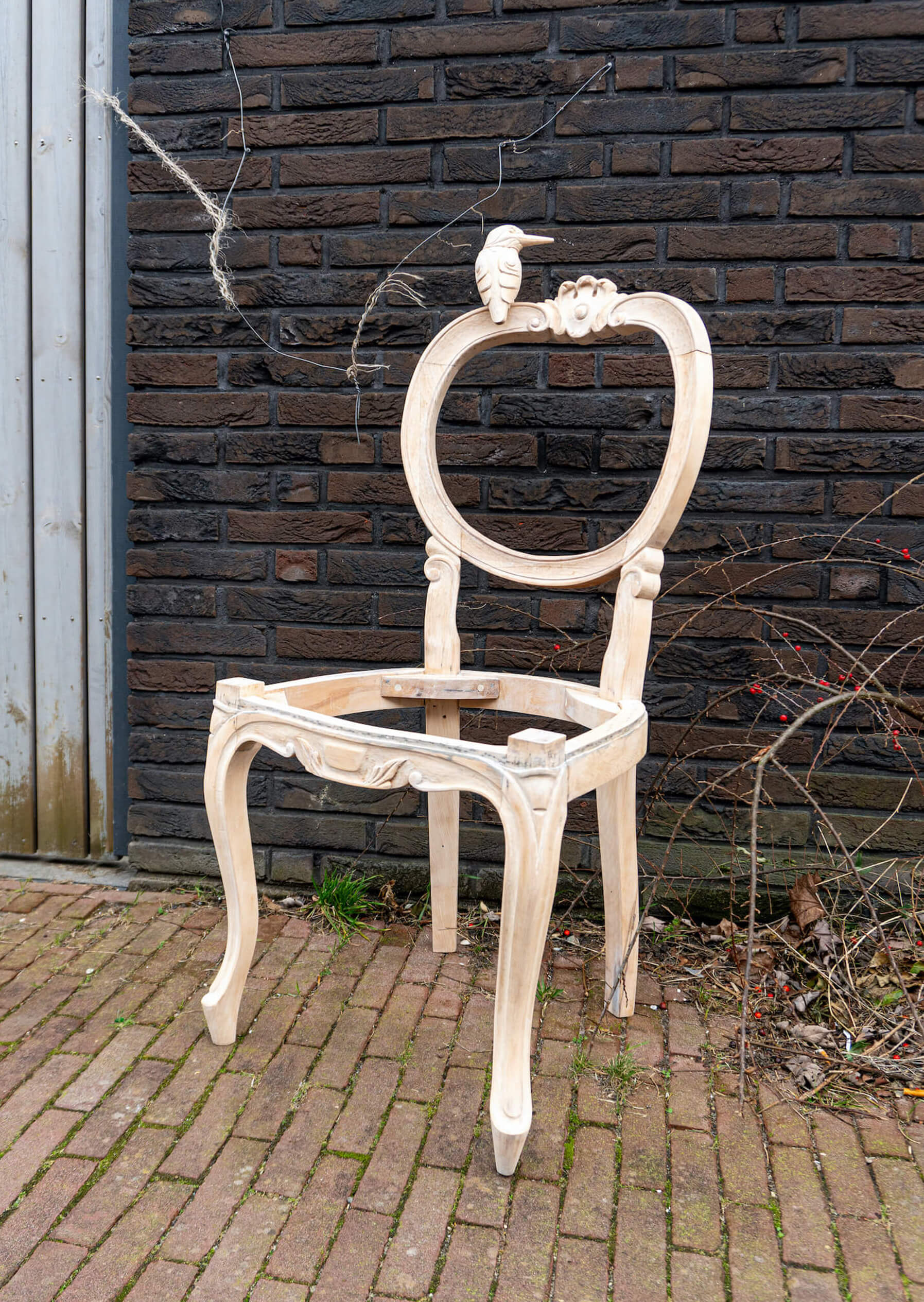 Bird and Chair wood sculpture by Teresa Hunyadi. Bird is inspired by a kingfisher. The photo was taken outside.