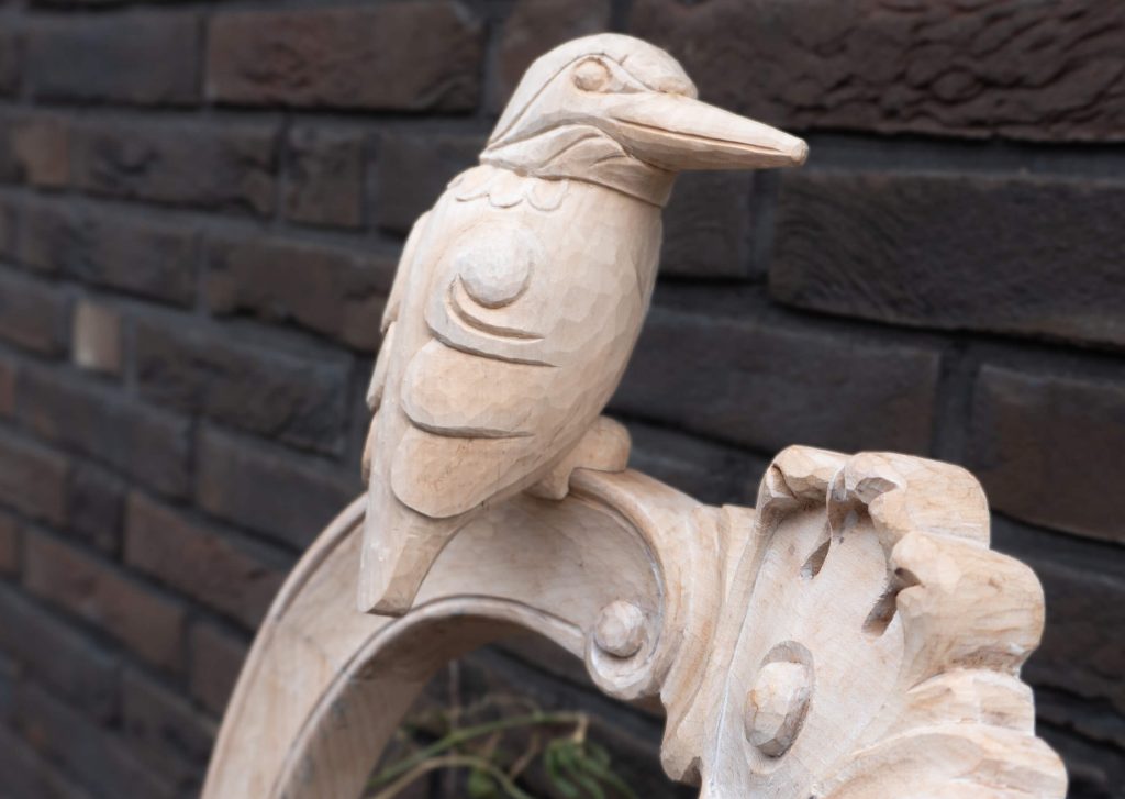 Detail of Bird and Chair wood sculpture by Teresa Hunyadi. Bird is inspired by a kingfisher. The photo was taken outside.